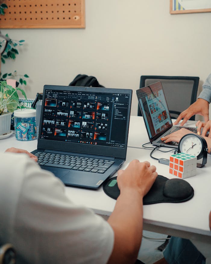 why-choose-us Two people working on laptops at a modern office desk with coffee and a Rubik's cube.