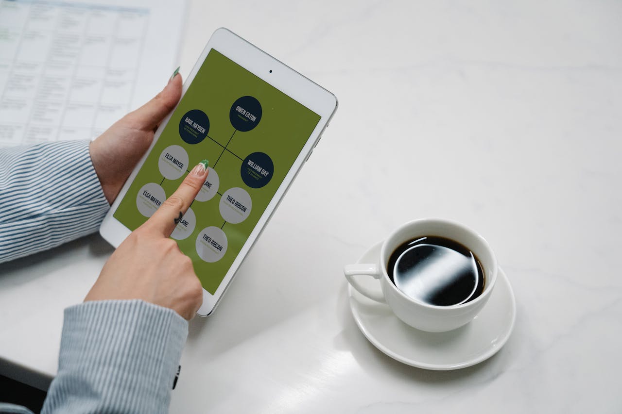 creative-01 Hands holding a tablet with a diagram, next to a cup of black coffee on a desk, symbolizing modern work life.